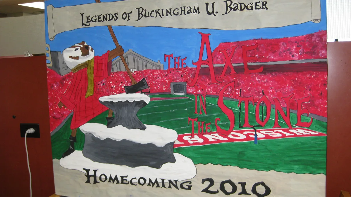 Hand-Painted Legends Homecoming Theme Banner in a Campus Library Painted homecoming banner showing a badger mascot pulling an axe from a stone in front of a red stadium crowd for a legends theme