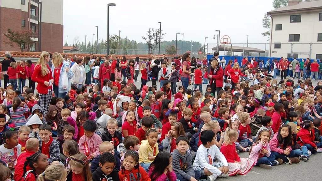 Large crowd of students and teachers wearing red seated on a school blacktop for a Red Ribbon Week opening ceremony