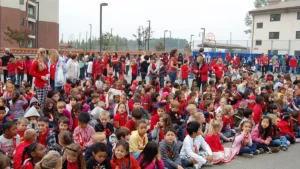 Large crowd of students and teachers wearing red seated on a school blacktop for a Red Ribbon Week opening ceremony