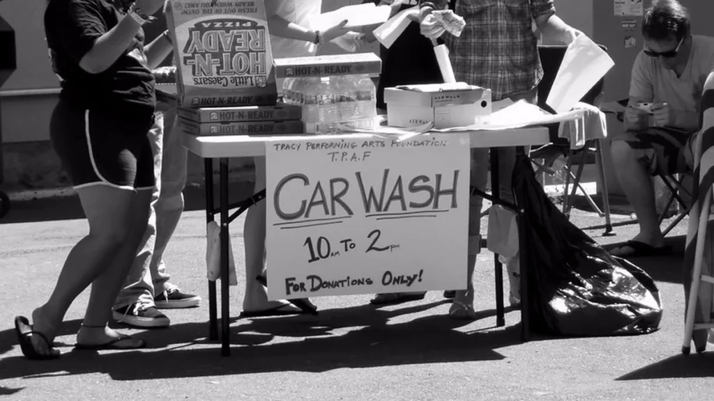 Hand lettered car wash sign reading 10 am to 2 pm for donations only on a folding table, a common student council fundraiser idea